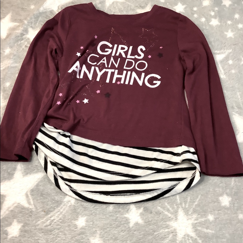 A purple shirt that says girls can do anything.